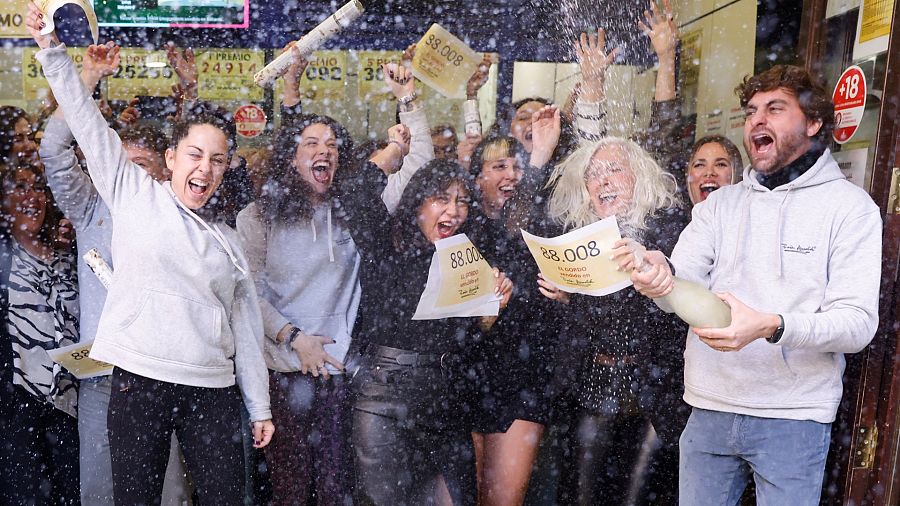 Varias personas celebran en la sucursal Doña Manolita de Madrid el Gordo del sorteo extraordinario de Navidad de la Lotería Nacional que ha recaído en el nº 88.008, este viernes. EFE/Aitor Martín