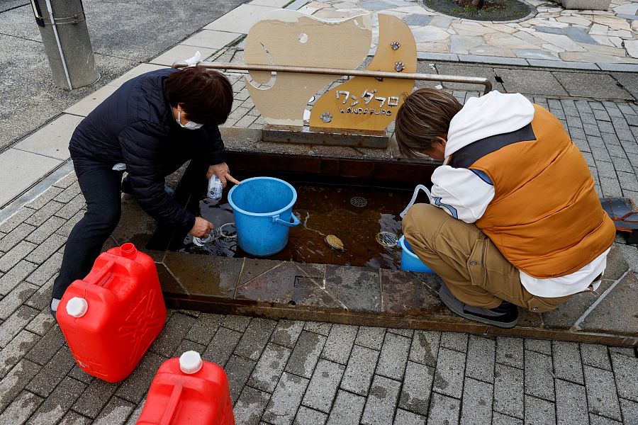 Varias personas recogen agua de un baño termal gratuito para mascotas en Wajima, Ishikawa
