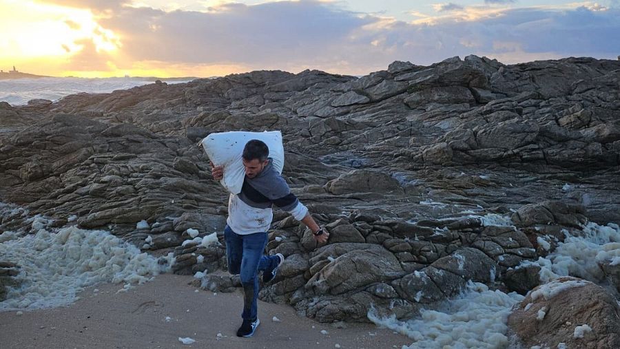 Rodrigo, primero en avistar los sacos, retira uno de ellos de la playa