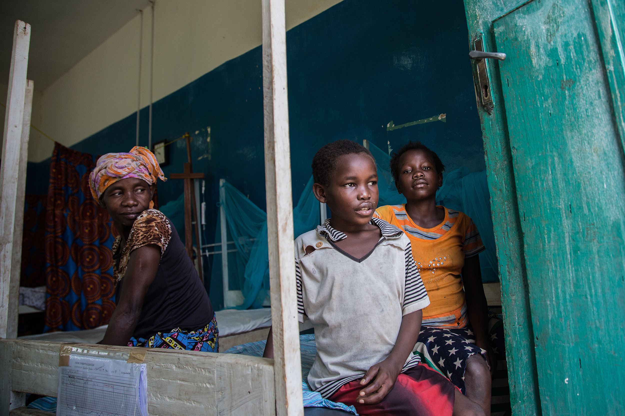 Séraphine, junto a su madre y hermana, permanece sentado en una de las camas del hospital de Lulingu.