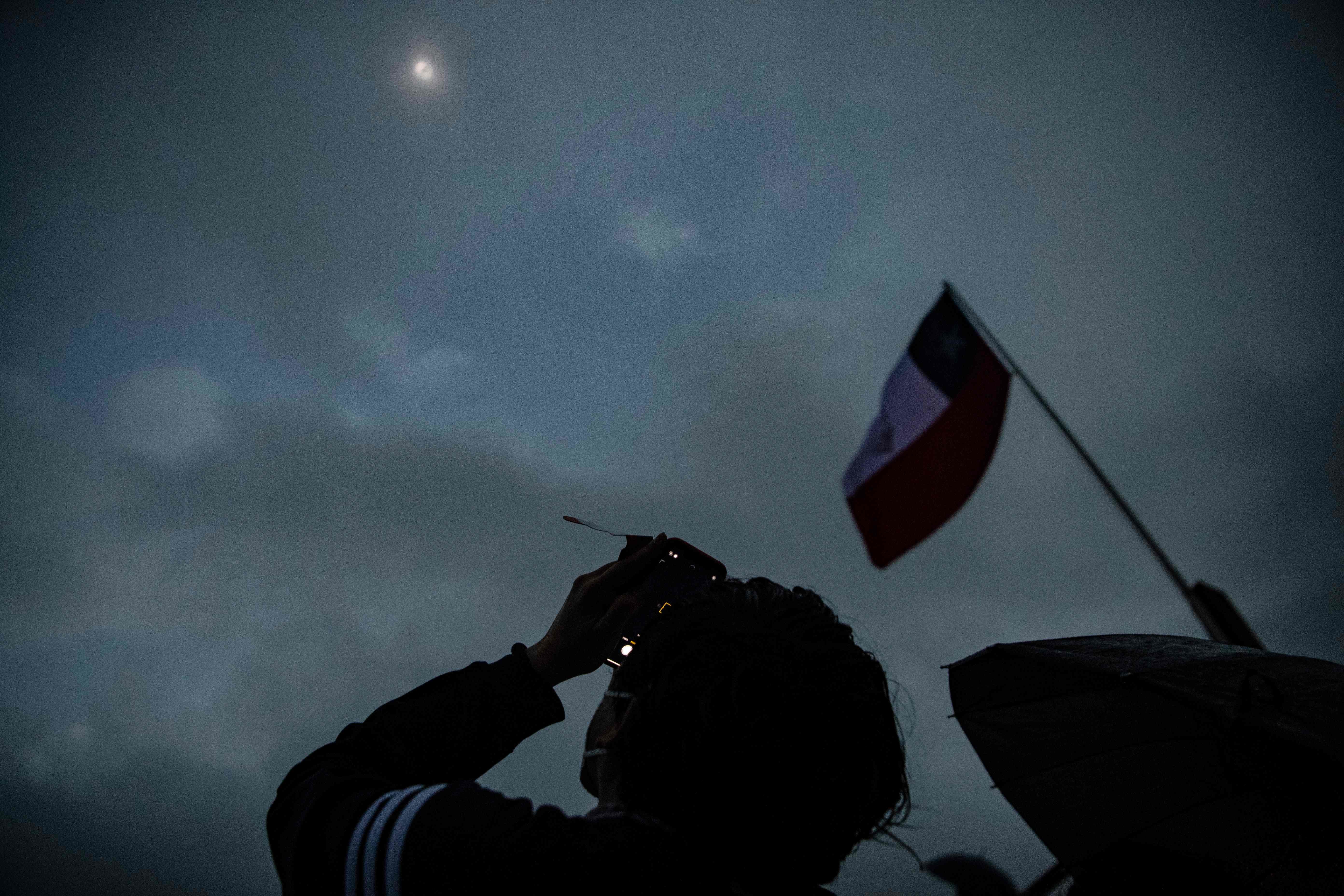 Un hombre fotografía el evento en Pucon, al sur de Chile, donde las lluvias y el mal tiempo han empañado el fenómeno. 