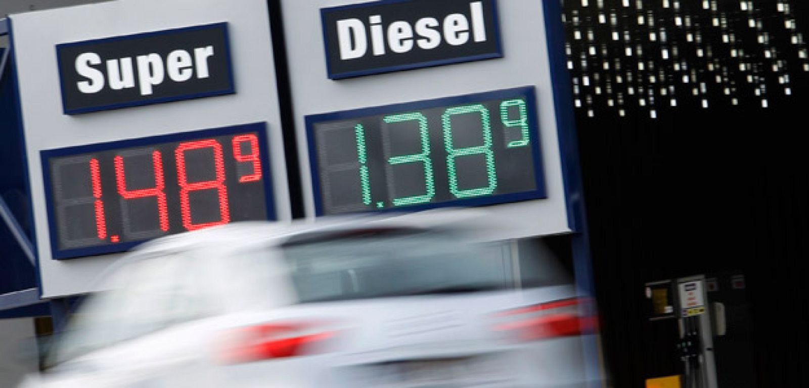 Un coche circula ante un cartel con precios de una gasolinera