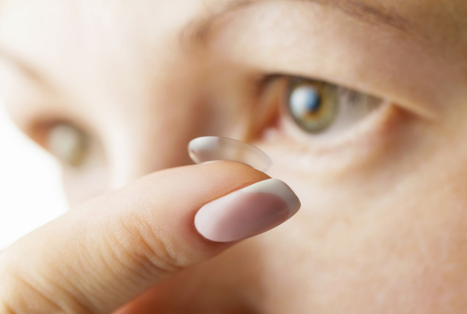 Una mujer poniéndose una lentilla de contacto.