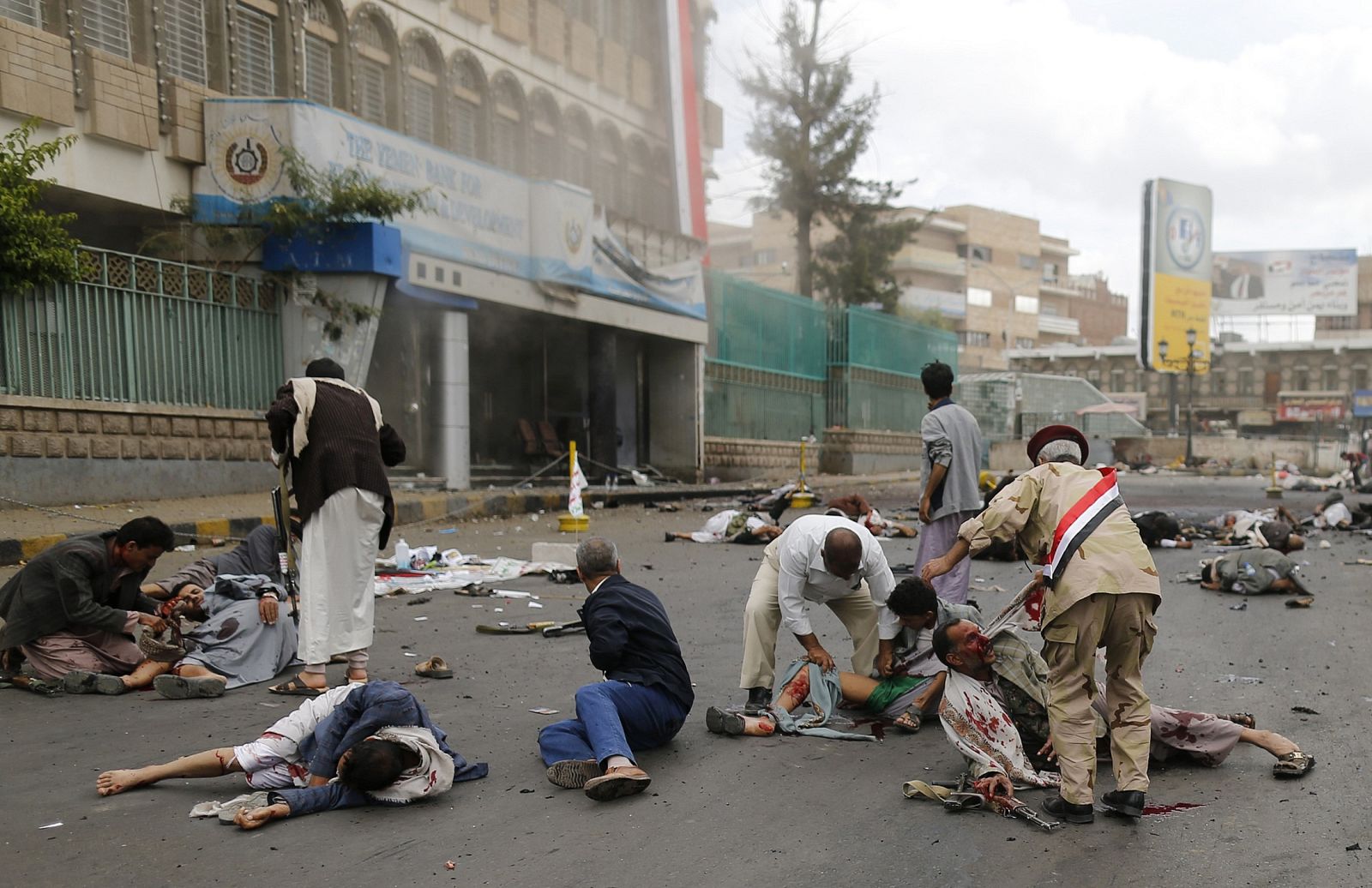 First responders check the wounded and the dead at the site of a suicide attack in Sanaa