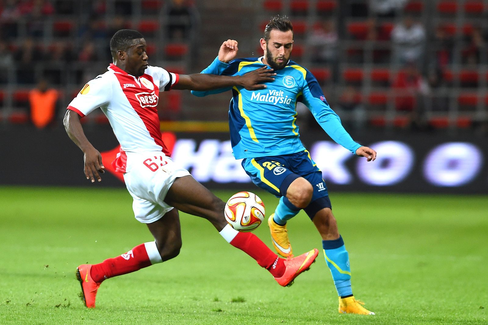 Geoffrey Mujangi Bia, del Standard, pugna con el sevillista Aleix Vidal