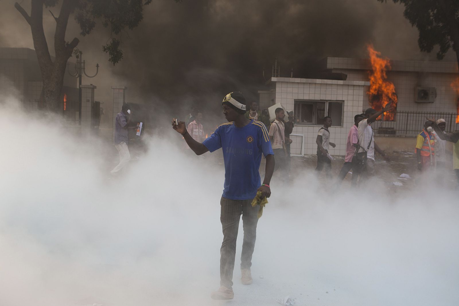 An anti-government protester films events with his cell phone outside the parliament building in Ouagadougou