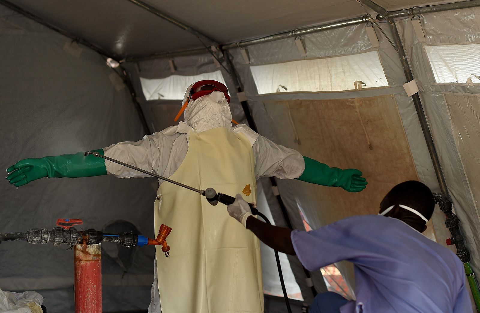 Un enfermero con un traje protector es desinfectado en Kenama, centro para el tratamiento del ébola en Sierra Leona