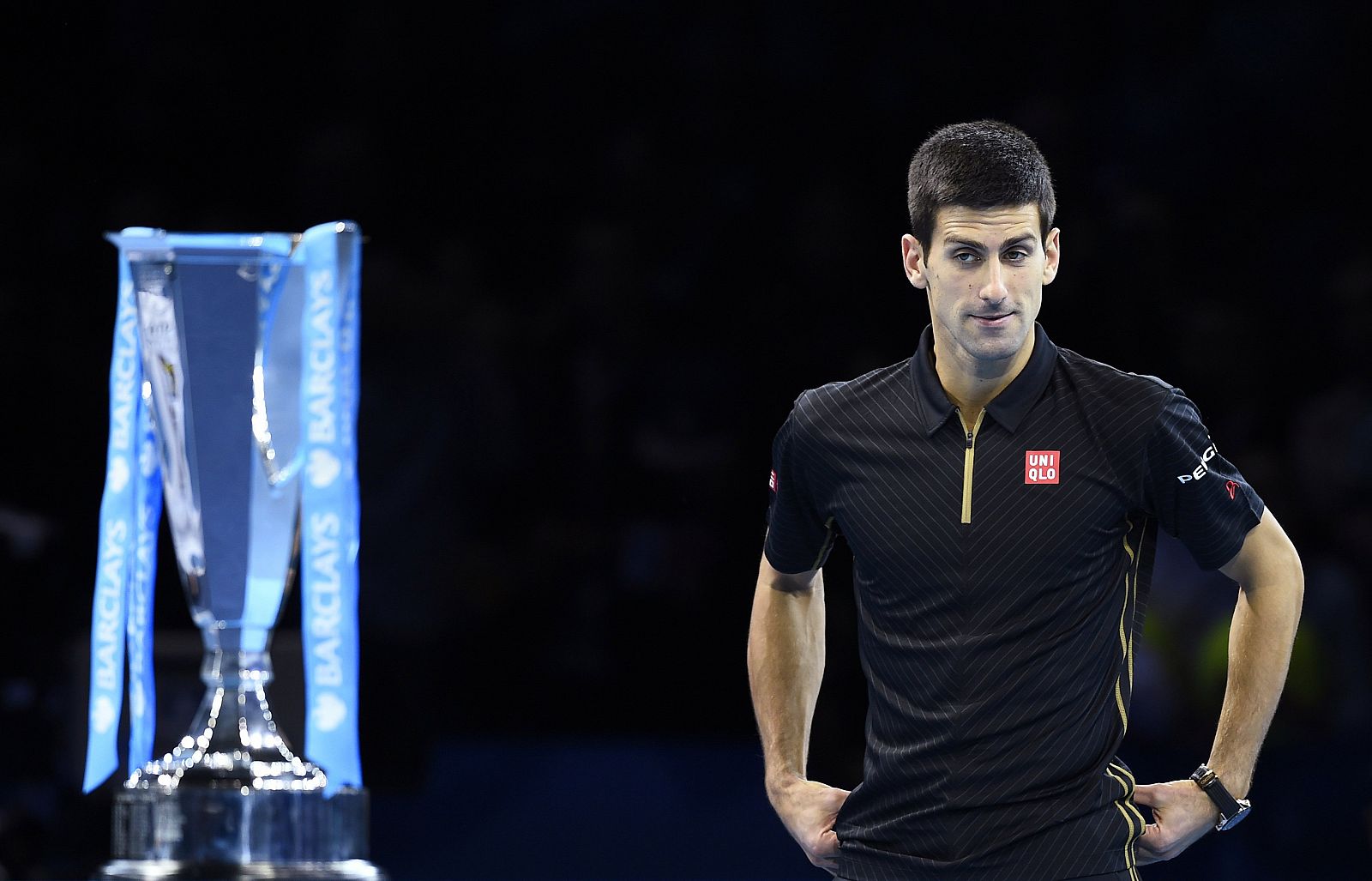 Novak Djokovic of Serbia looks at the trophy after Roger Federer of Switzerland forfeited due to injury in the men's singles final at the ATP World Tour Finals at the O2 in London