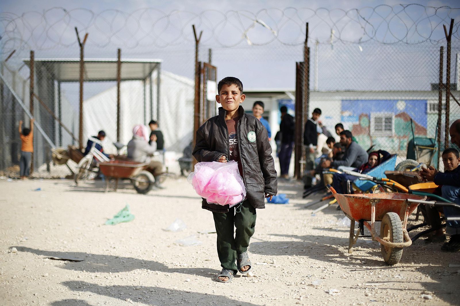 Syrian children wait to carry customers' goods with wheelbarrows in front of the Tazweed Center at the Al-Zaatari refugee camp in the Jordanian city of Mafraq