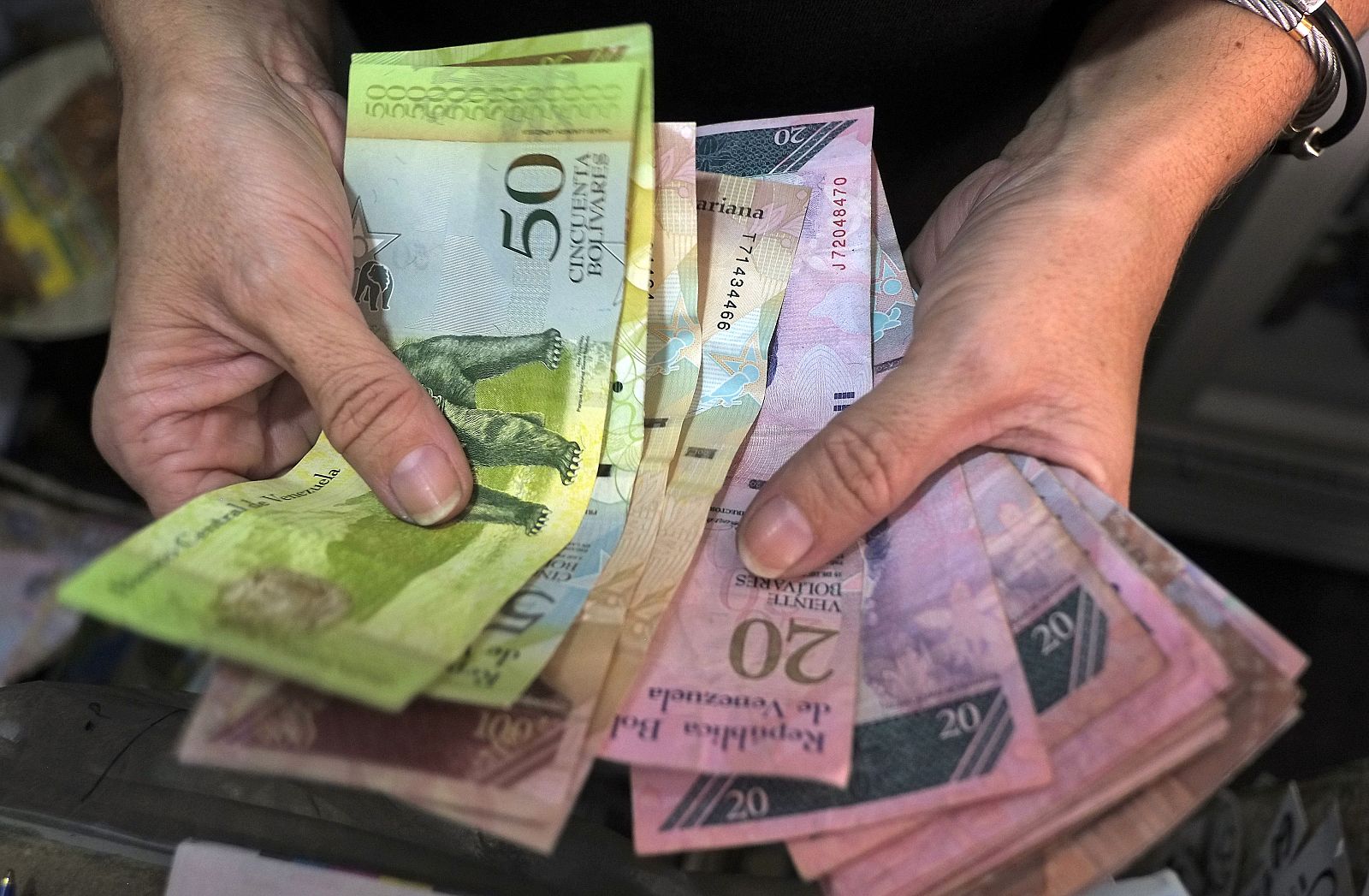 Un comerciante muestra billetes de Bolívar en su tienda de Caracas