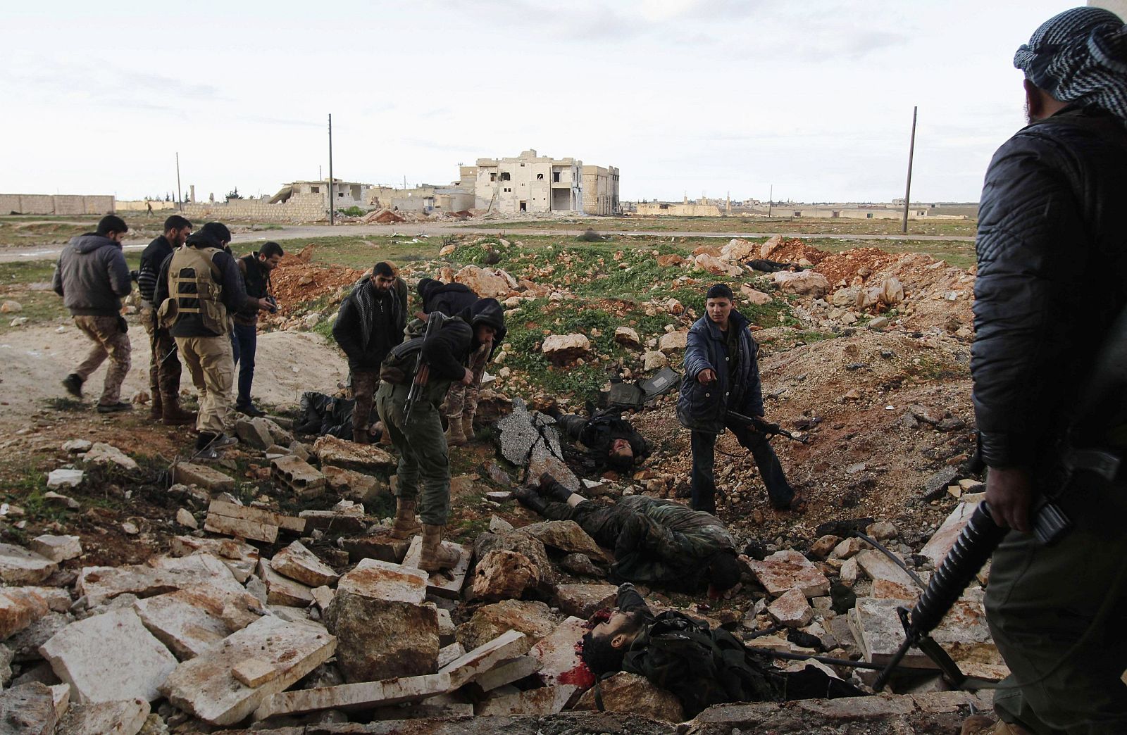 Combatientes rebeldes sirios miran los cadáveres, que según ellos pertenecían a las fuerzas leales al presidente de Siria, Bashar al-Assad