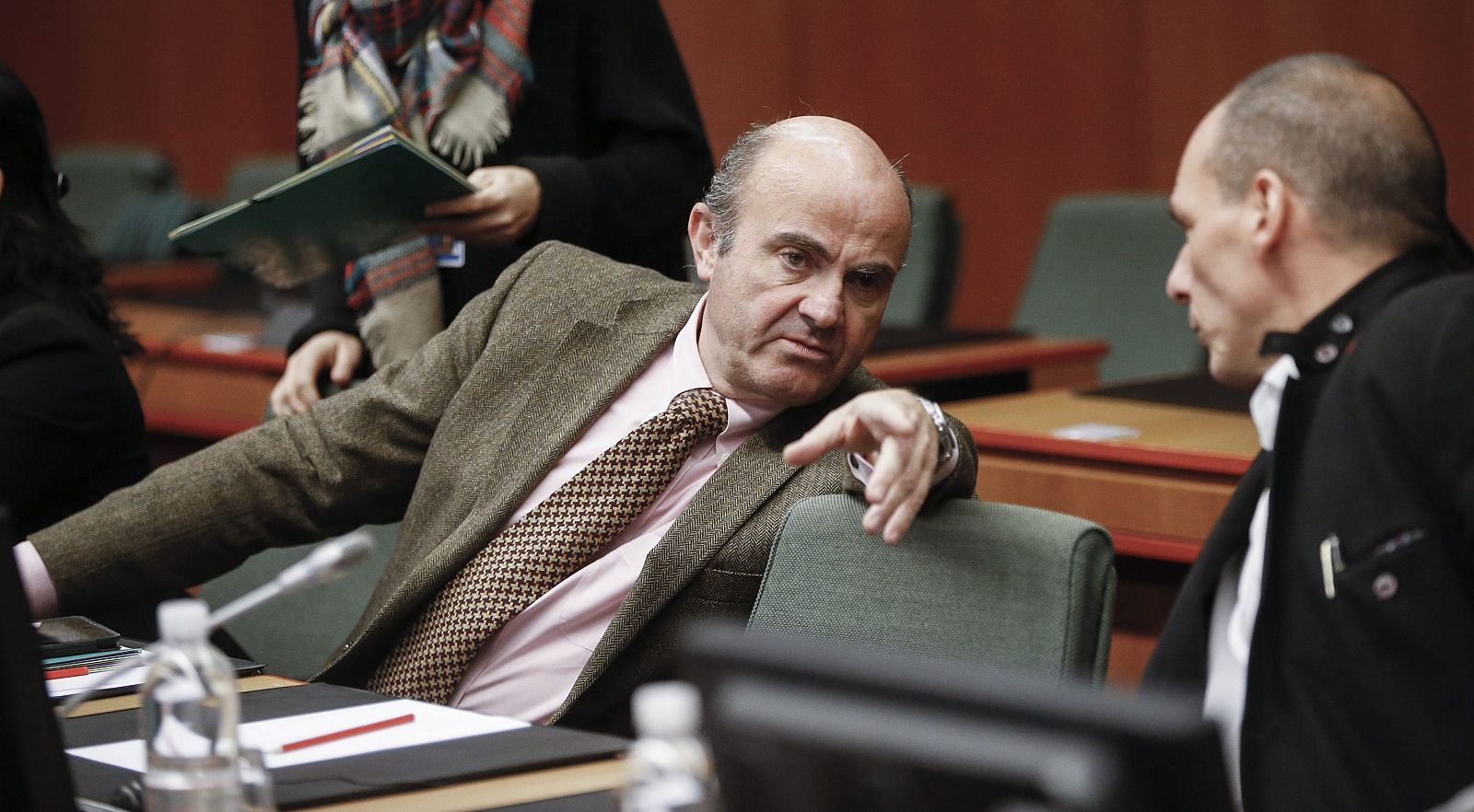 El ministro de Economía y Competitividad, Luis de Guindos, conversa con su homólogo griego Yanis Varufakis, durante la reunión extraordinaria del Eurogrupo.