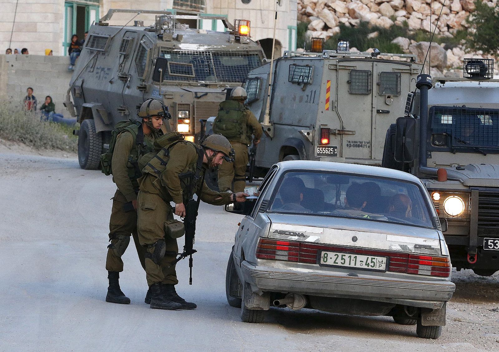 Israeli soldiers stop a car as they search for a missing Israeli near the West Bank city of Hebron