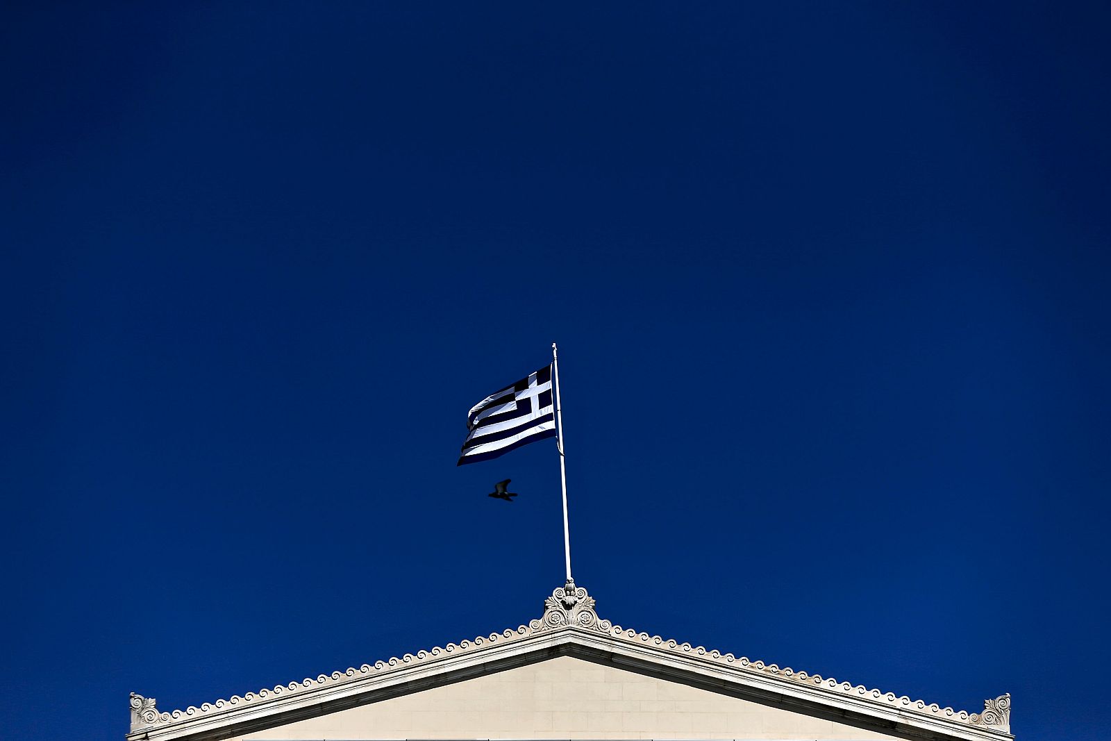 A Greek national flag flutters atop the parliament building in Athens. Imagen de la bandera griega sobre el parlamento heleno.