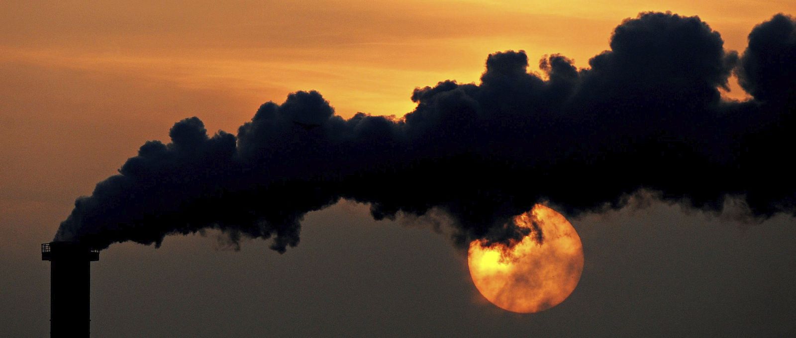Un atardecer tras el humo que se desprende de una chimenea en Wismar (Alemania)