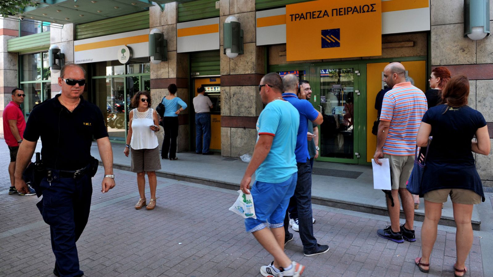 Un grupo de clientes hacen cola ante un cajero automático en Atenas