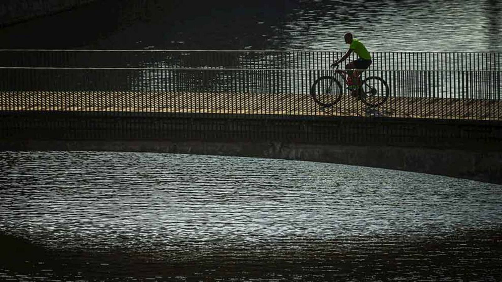 Un hombre con su bicileta pasea por el parque de Madrid Río de la capital