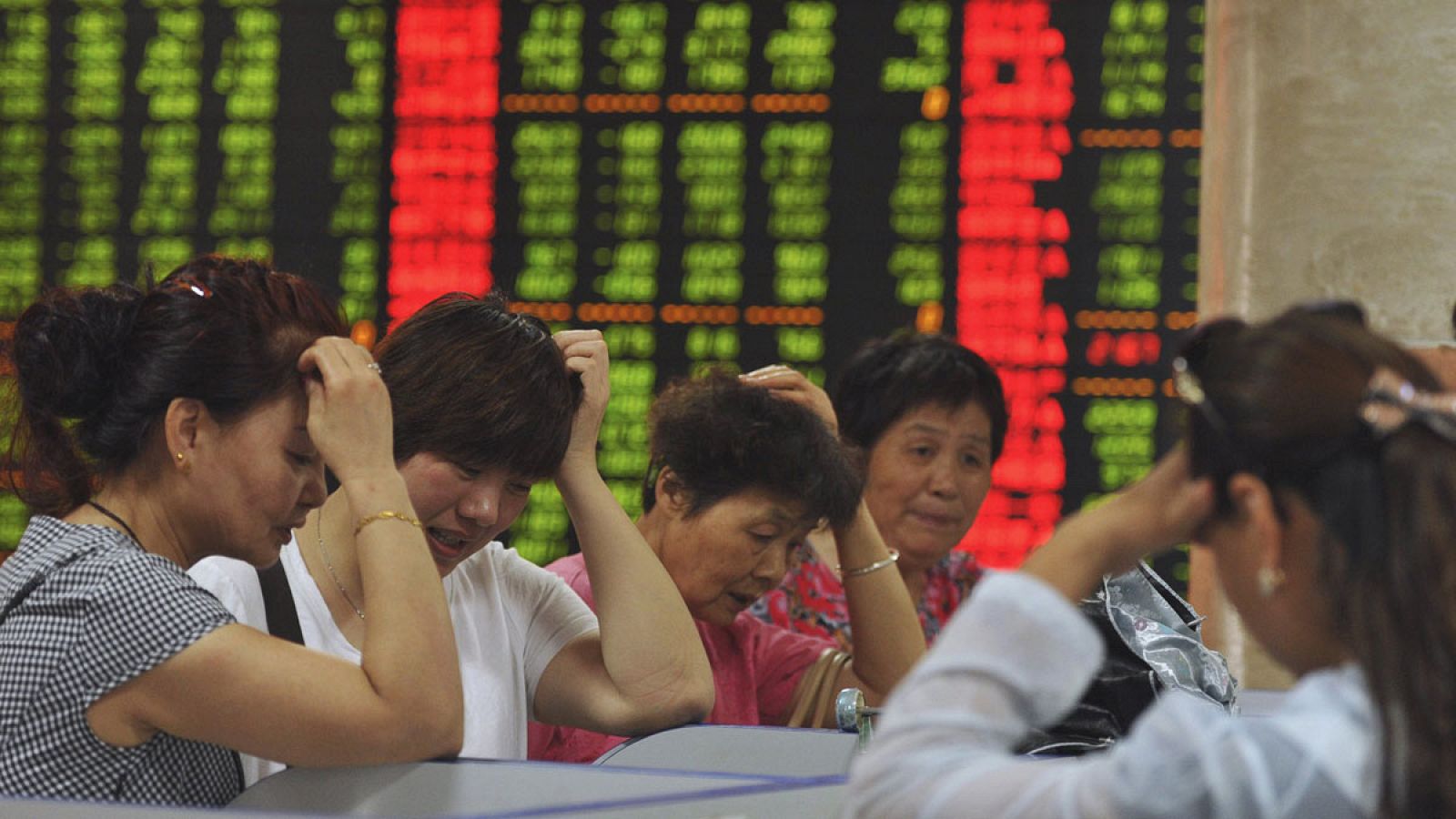 Pequeños inversores observan las pantallas con información bursátil en la localidad china de Fuyang