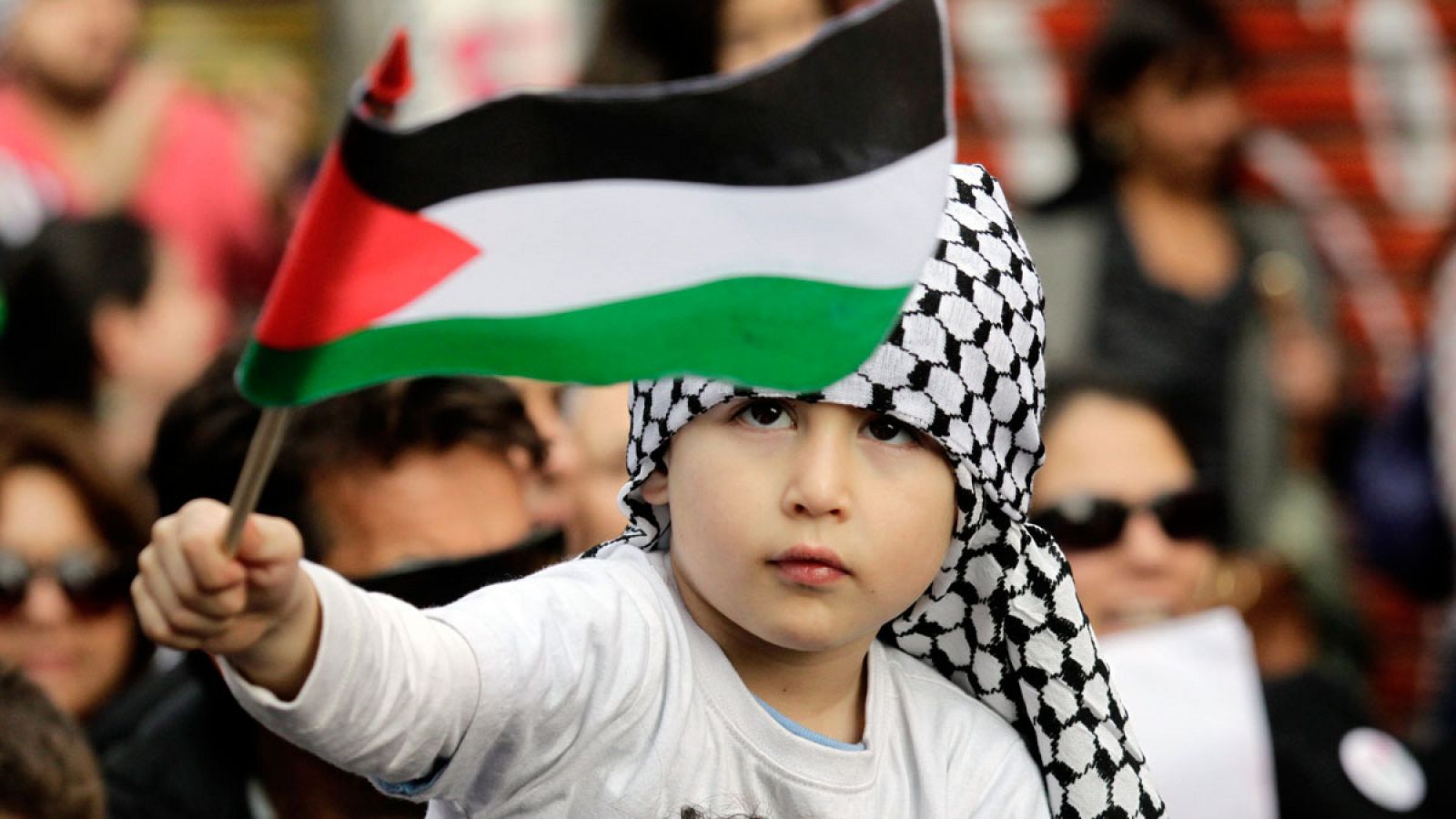 Un niño de la comunidad Palestina en Chile sostiene una bandera en una marcha en apoyo a Palestina.