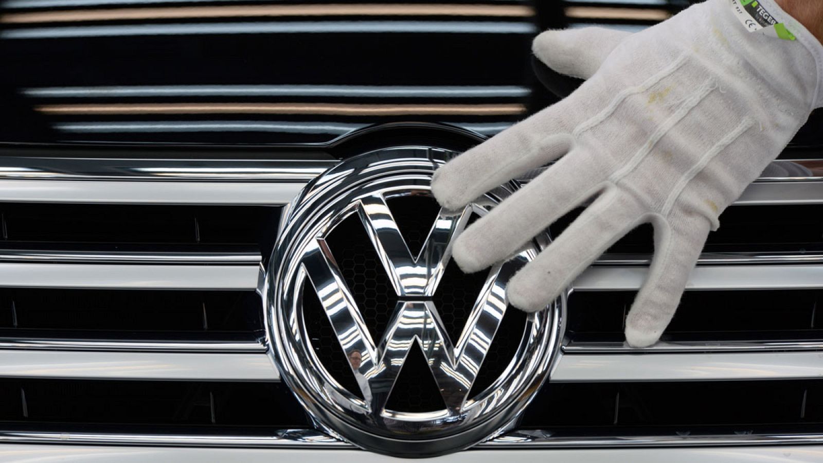 Un empleado de Volkswagen toca el logo de un vehículo en la 'fábrica transparente' de la compañía en Dresde