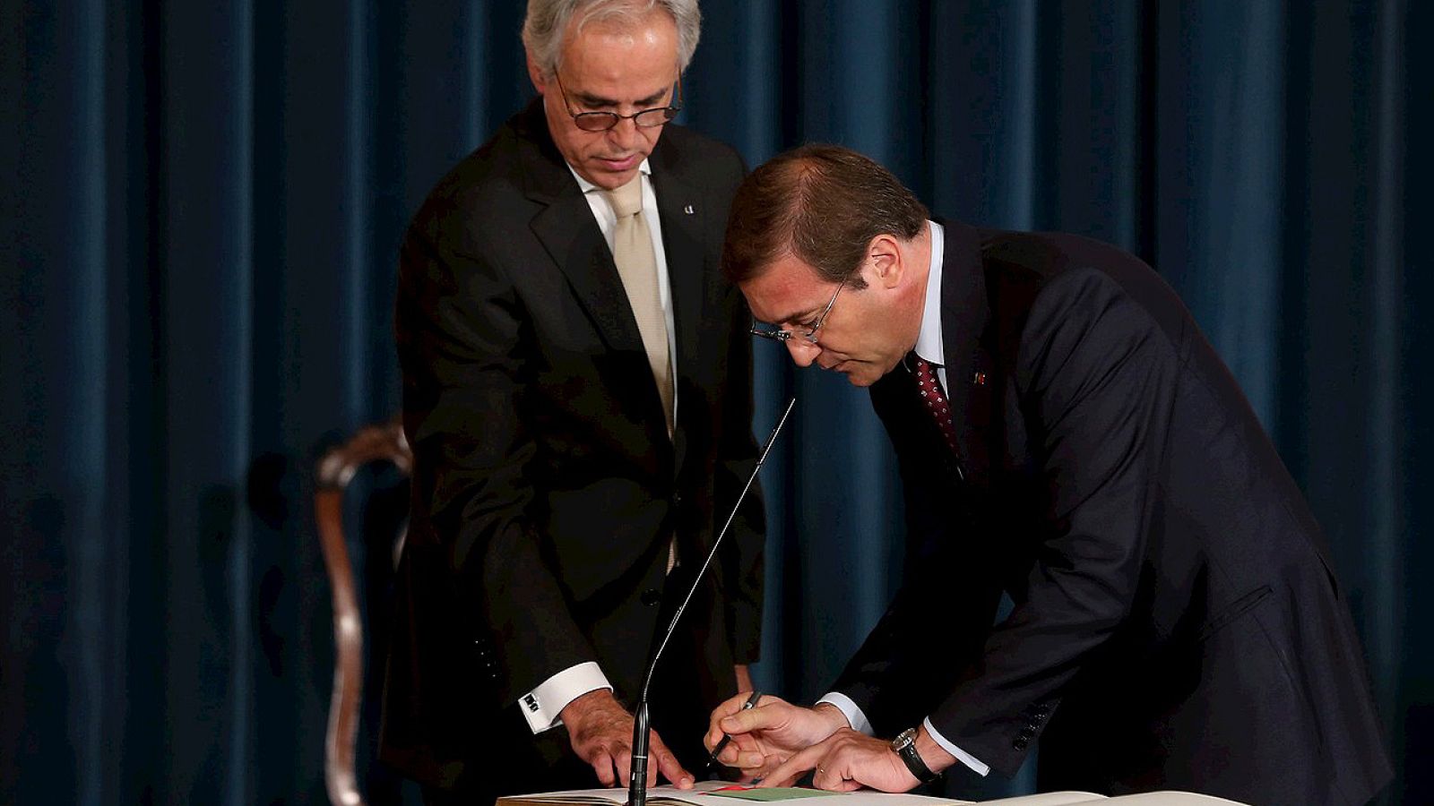 El primer ministro portugués, Pedro Passos Coelho (d), firma durante la ceremonia de su investidura celebrada en el Palacio de Ajuda en Lisboa (Portugal)