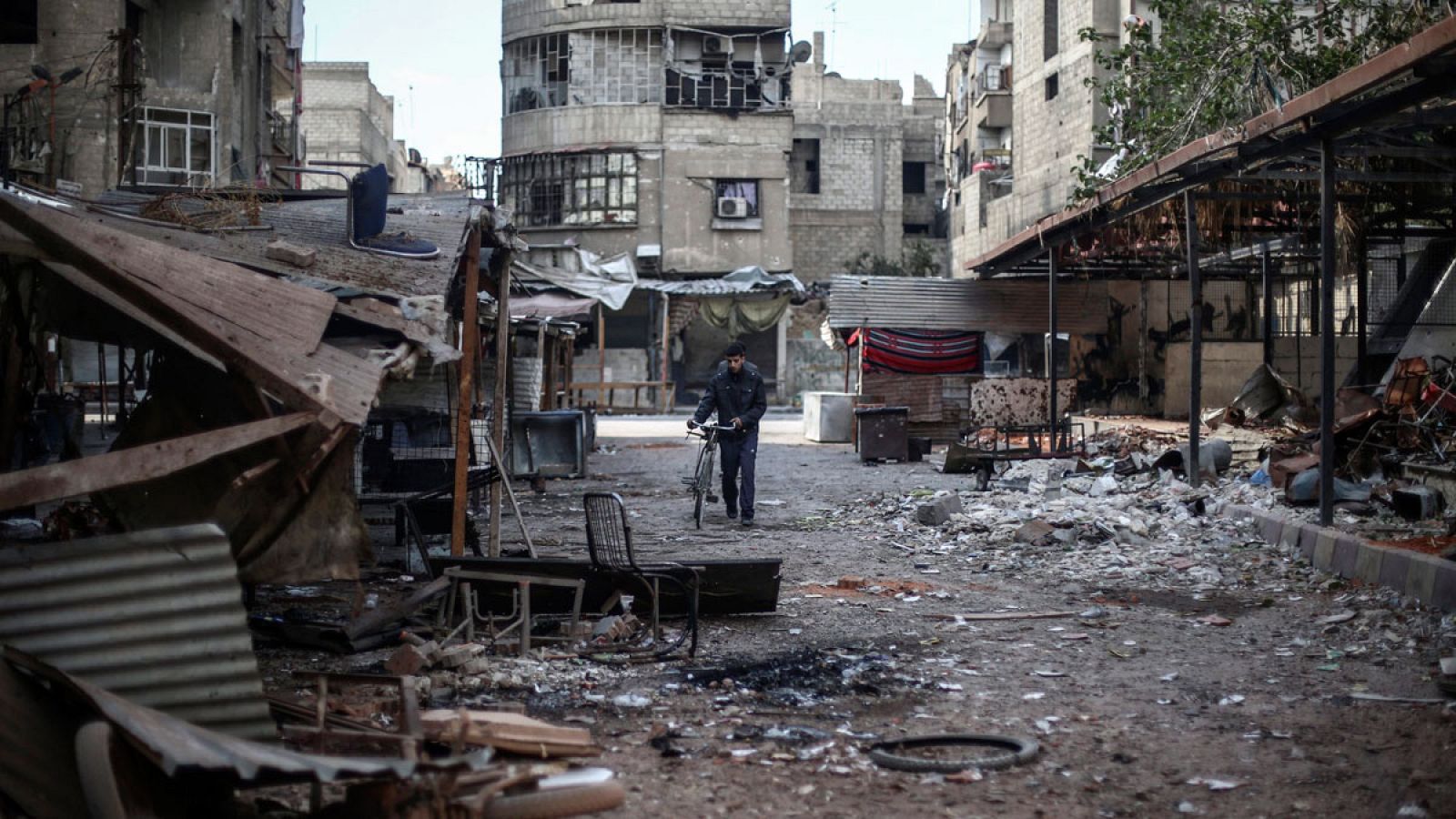Un ciudadano pasa con su bicicleta entre los escombros en un mercado tras un ataque de las fuerzas del régimen sirio en Duma, a las afueras de Damasco el pasado octubre.