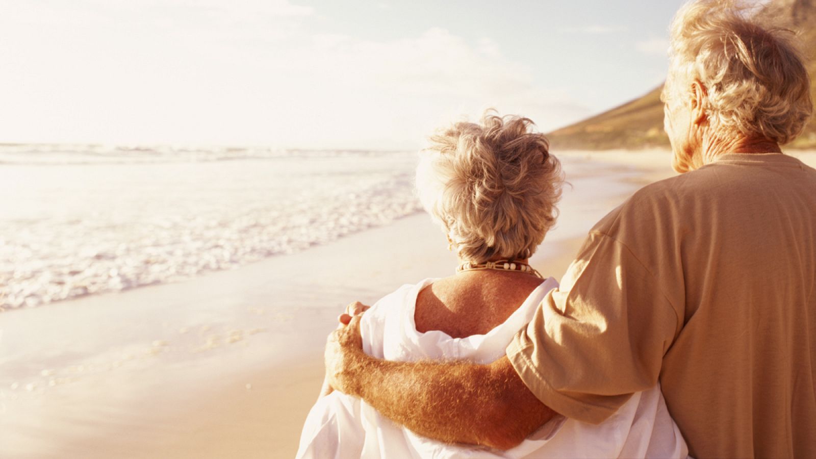 Una pareja de jubilados pasea por la playa
