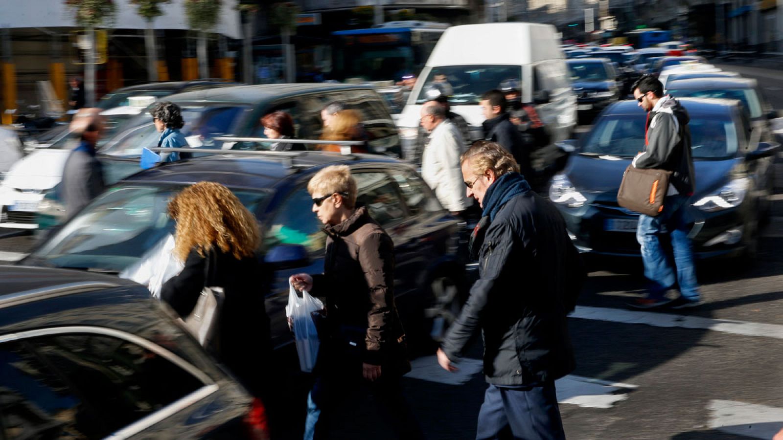 Varias personas cruzan por un paso de peatones de la Gran Vía de Madrid