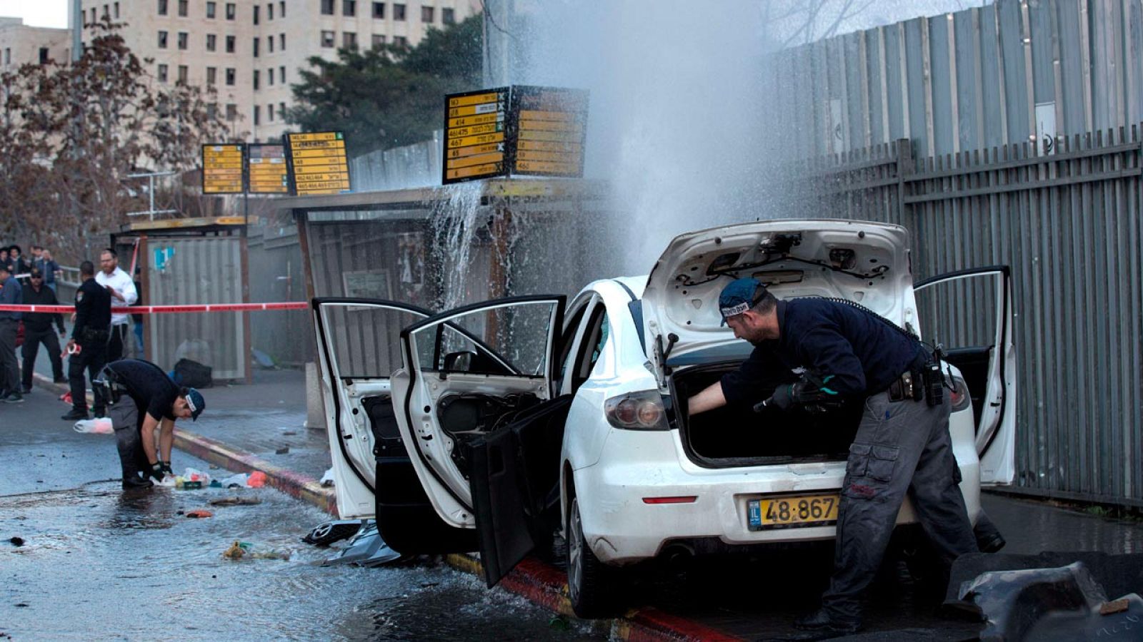 La policía israelí inspecciona el coche con el que un palestino ha embestido una parada de autobús en Jerusalén, antes de ser abatido