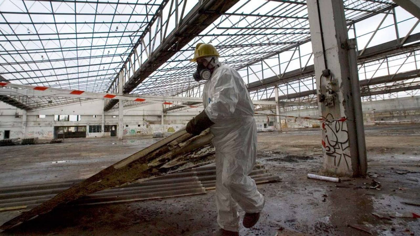 Un operario retira restos de uralita con amianto de una nave en ruinas
