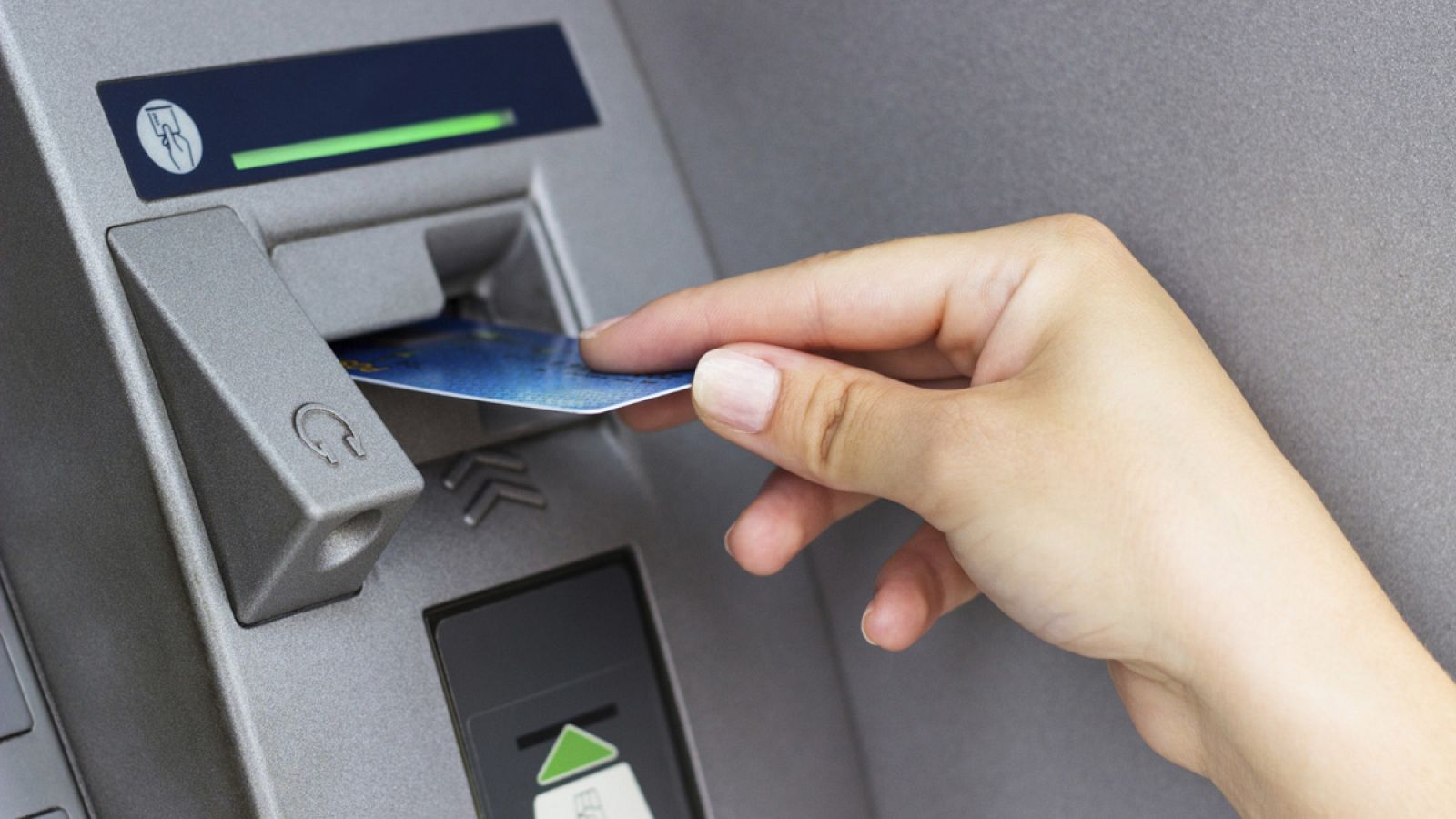 Una persona introduce su tarjeta de débito en un cajero automático