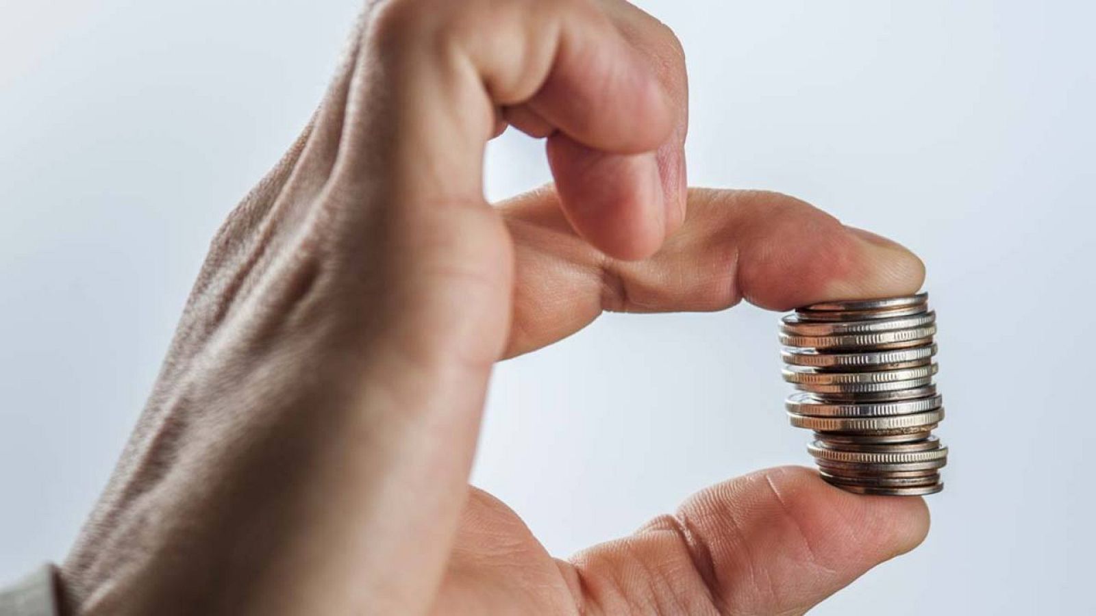 Un hombre sujeta entre sus dedos un taco de monedas