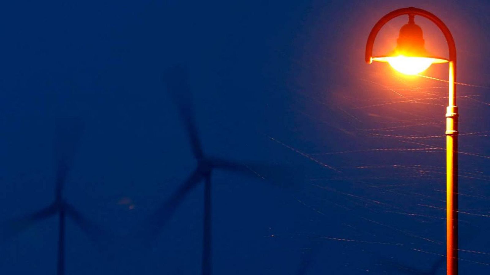 Una farola encendida delante de unos aerogeneradores