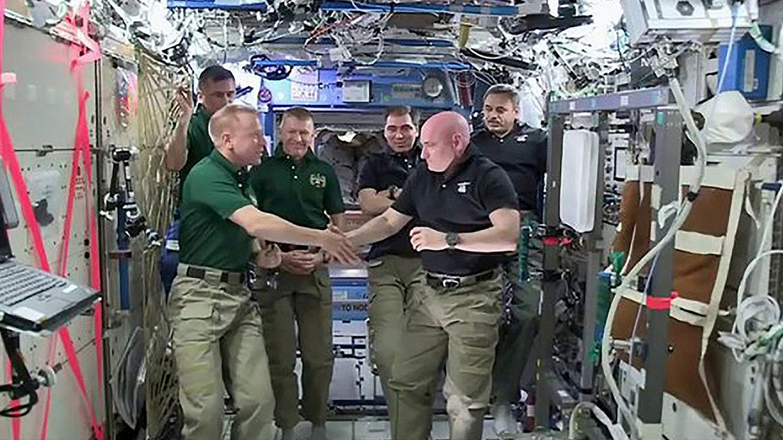 Los astronautas Scott Kelly (derecha) y Tim Kopra se dan la mano en el cambio de mando en la Estación Espacial Internacional, antes de que Kelly regrese a la tierra junto a los rusos Mijail Kornienko y Serguei Volkov