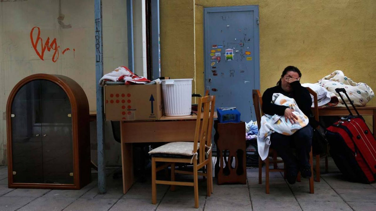 Una mujer sentada junto a sus enseres en el patio del edificio donde vivía de alquiler antes de ser desahuciada