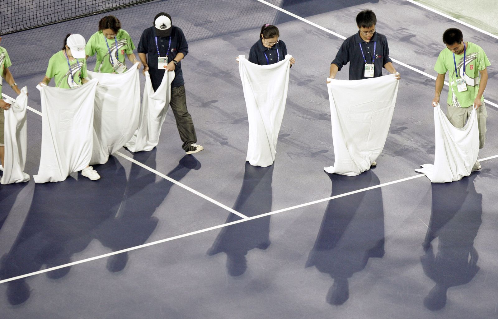 Los voluntarios intentan secar la pista con toallas.