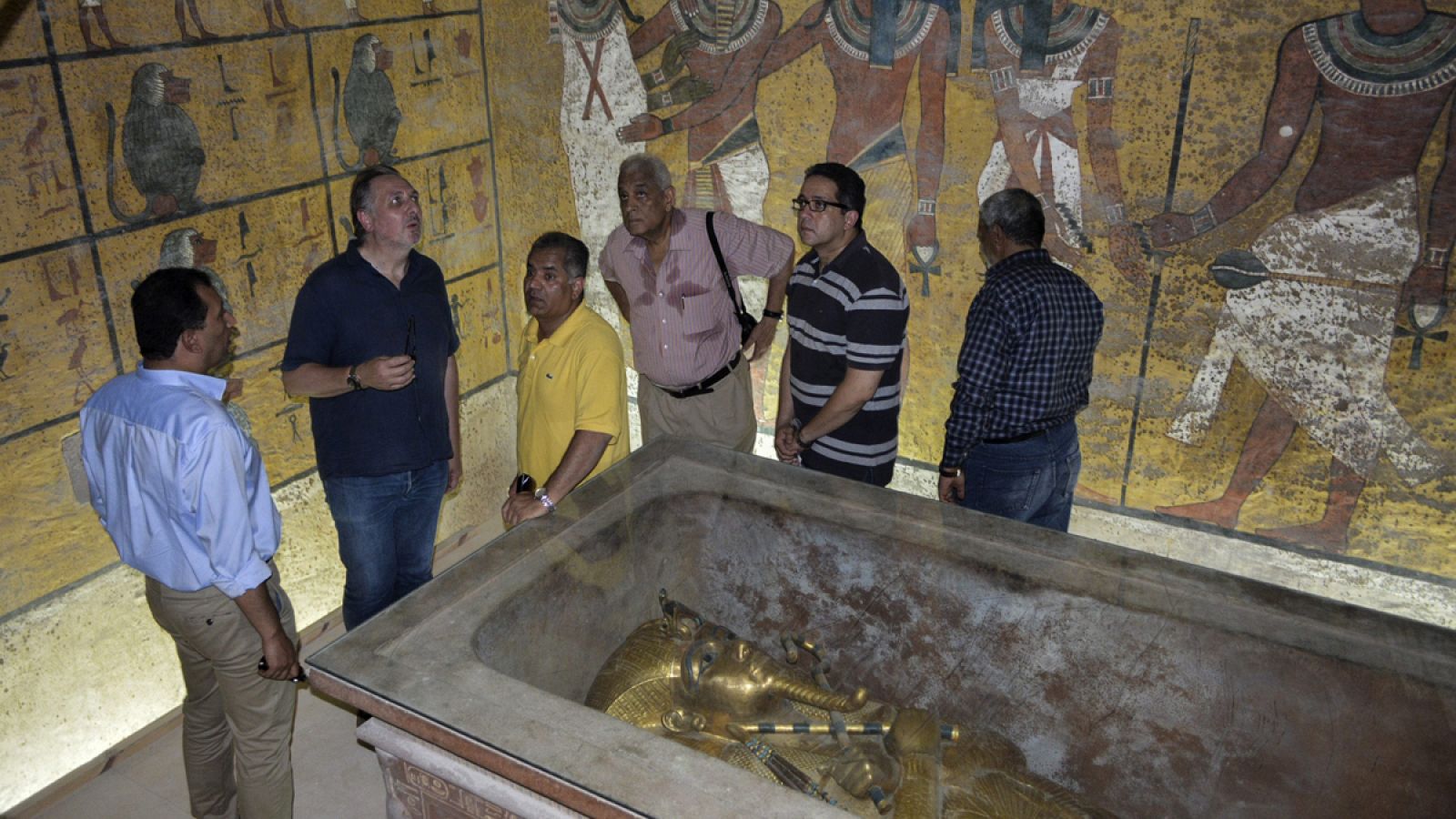 El egiptólogo británico Nicholas Reeves (2i) y el exministro de Antigüedades, Mamduh al Damati (3i), conversan frente al sarcófago de Tutankamón.