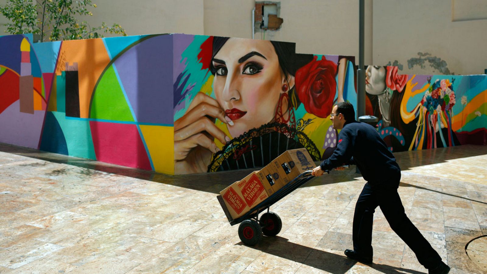 Un camarero empuja una carretilla con cajas de bebidas en Málaga