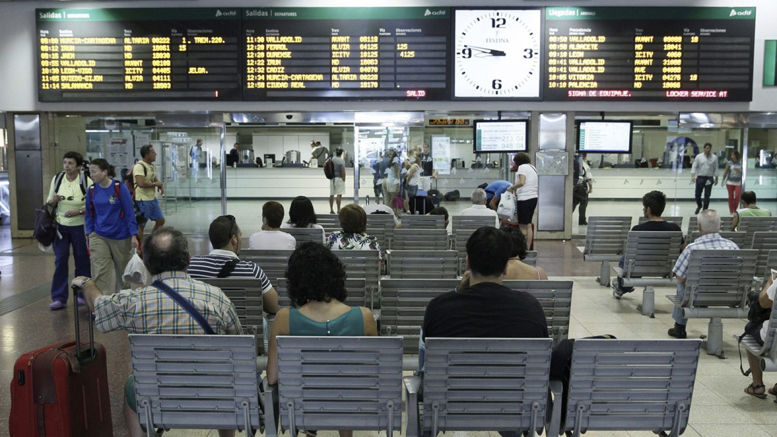 Varios pasajeros esperan la llegada de sus trenes ante las pantallas informativas en la estación de Chamartín, en Madrid
