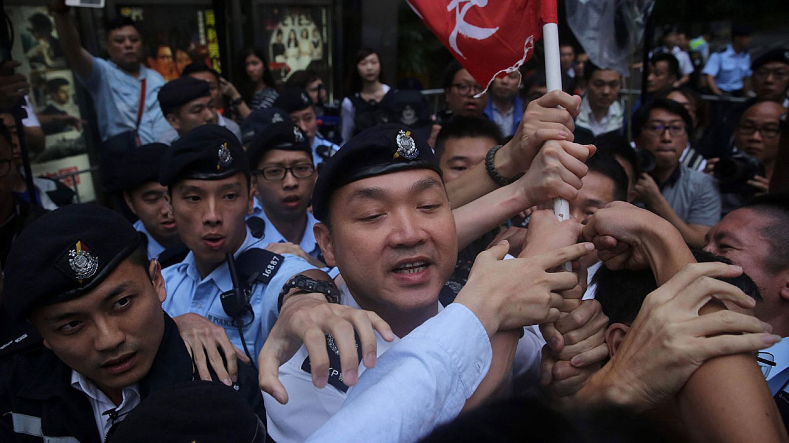 La policía intenta confiscar una bandera durante una concentración de protesta en Hong Kong por la visita del dirigente chino Zhang Dejiang