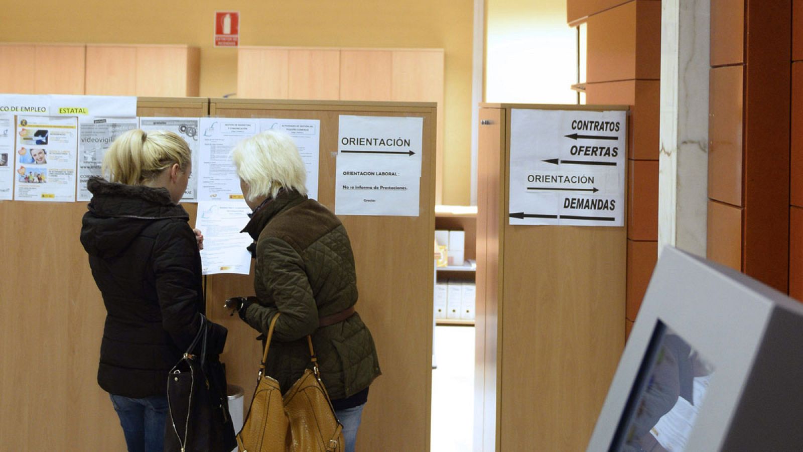 Dos mujeres consultan un tablón de anuncios en una oficina de empleo