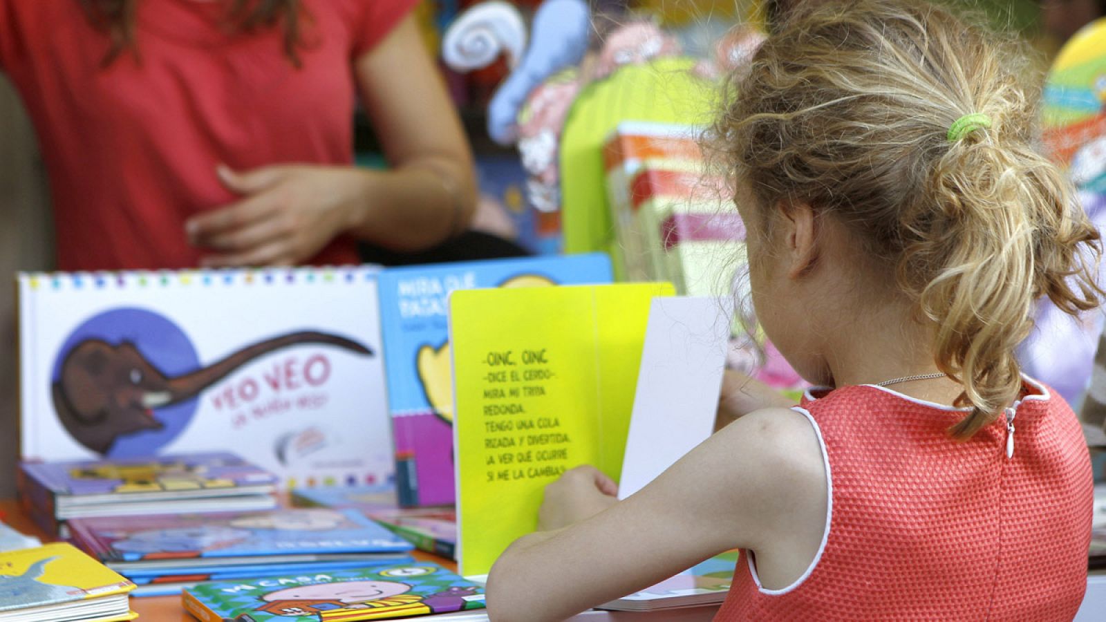 Una niÃ±a hojea un libro en una de las casetas de la 75 ediciÃ³n de la Feria del Libro de Madrid.
