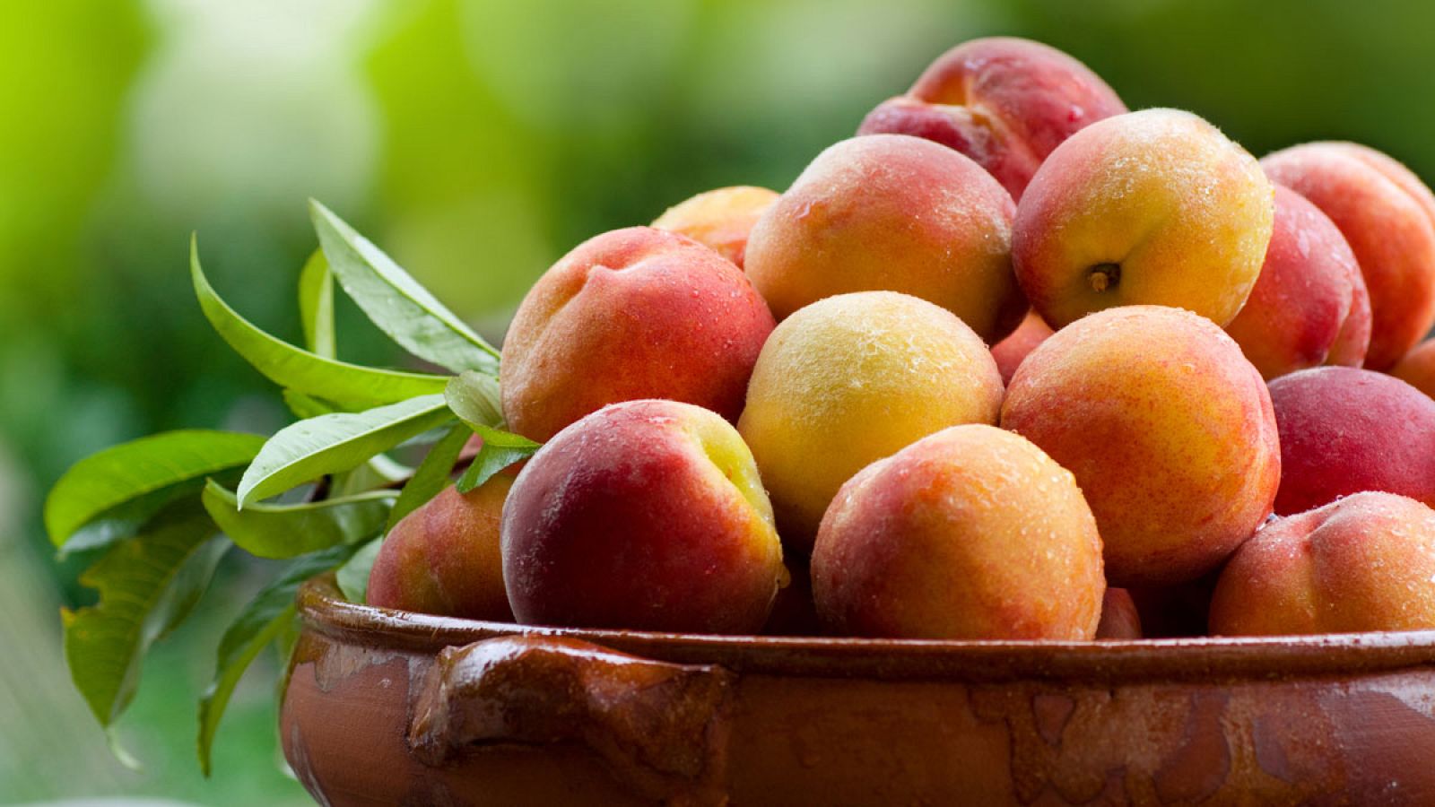 Un recipiente de barro lleno de melocotones