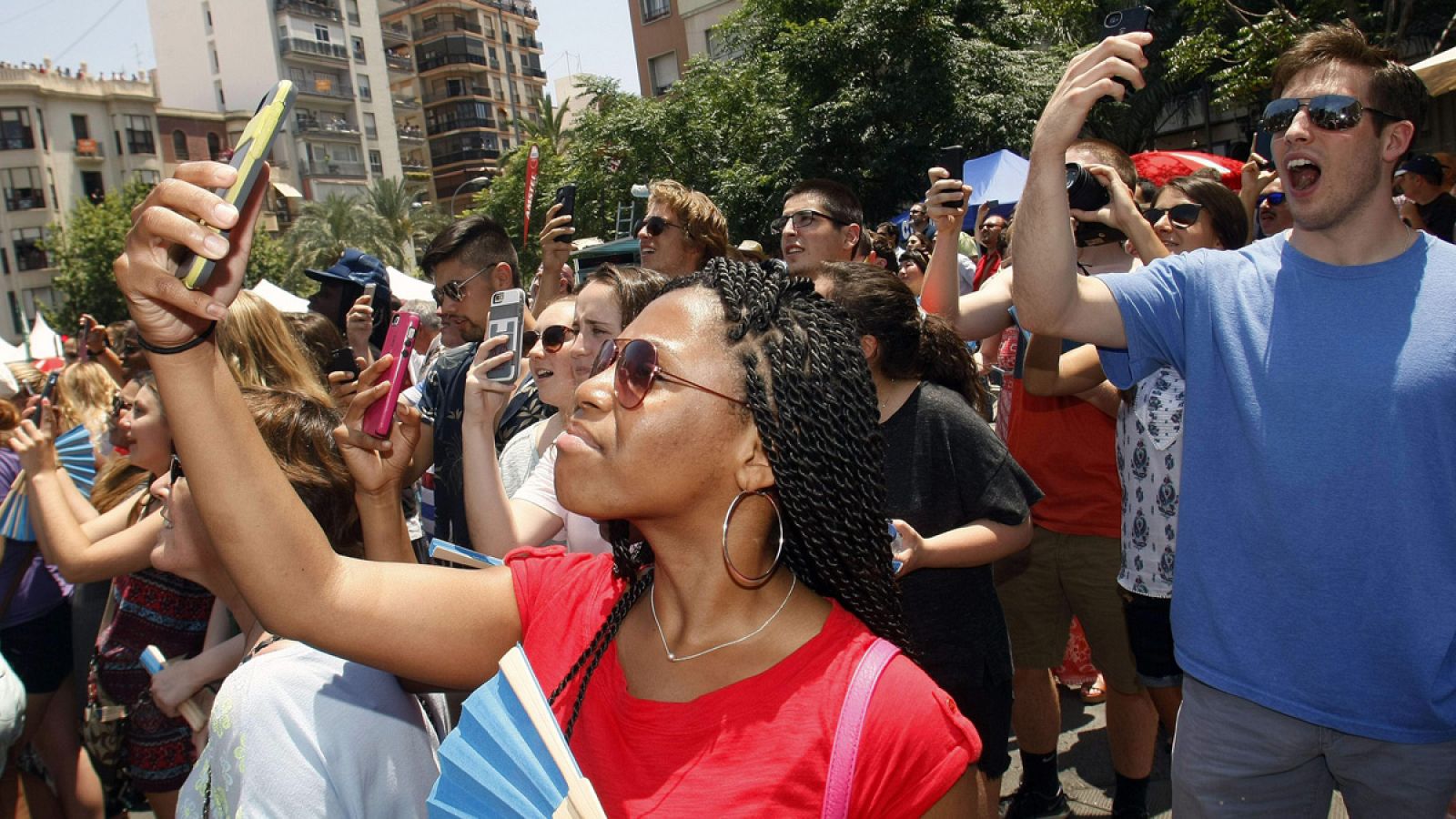 Un grupo de turistas graba con sus móviles el disparo de la quinta mascletá de las Hogueras en la Plaza de Los Luceros de Alicante