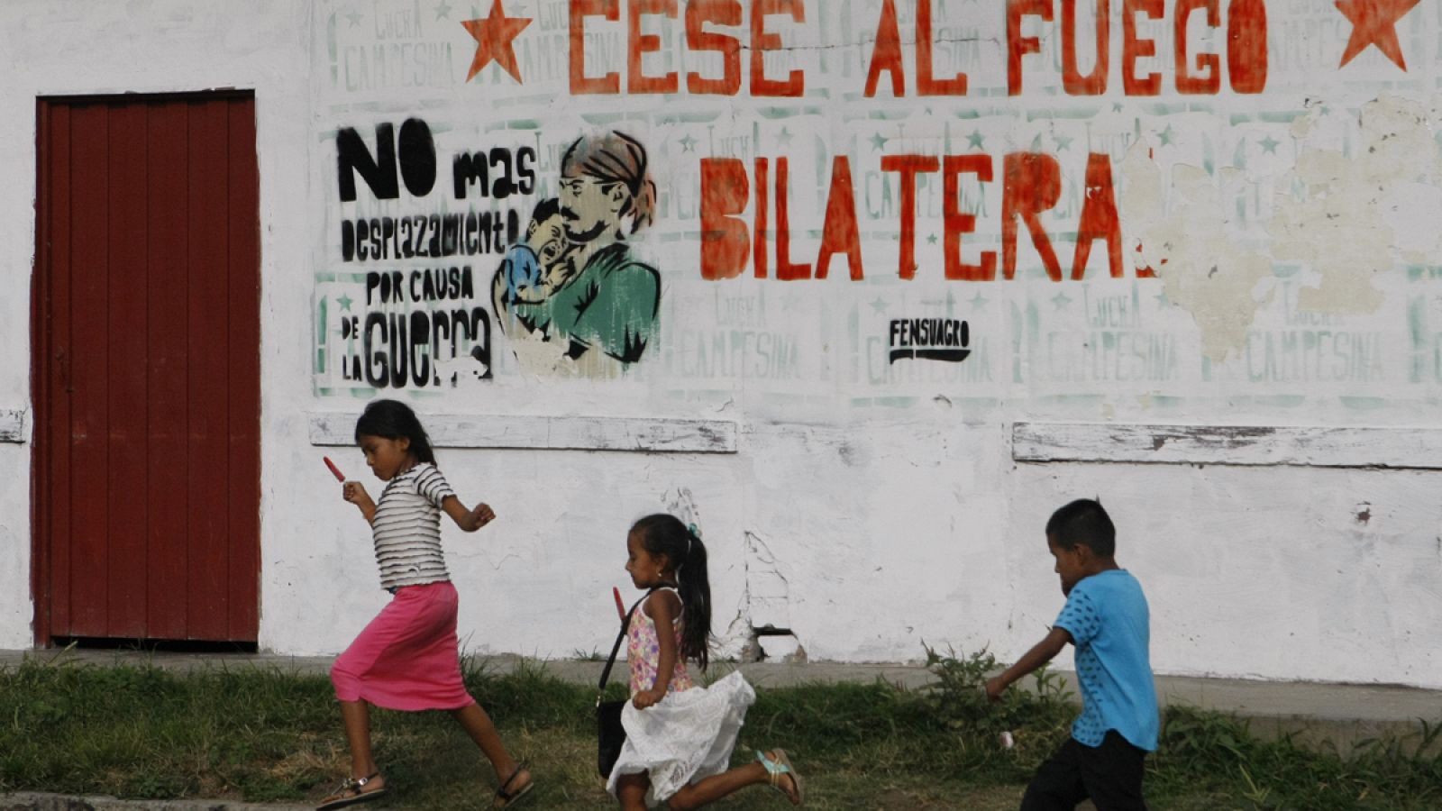 Niños pasando frente a una pintada por la paz en Colombia.