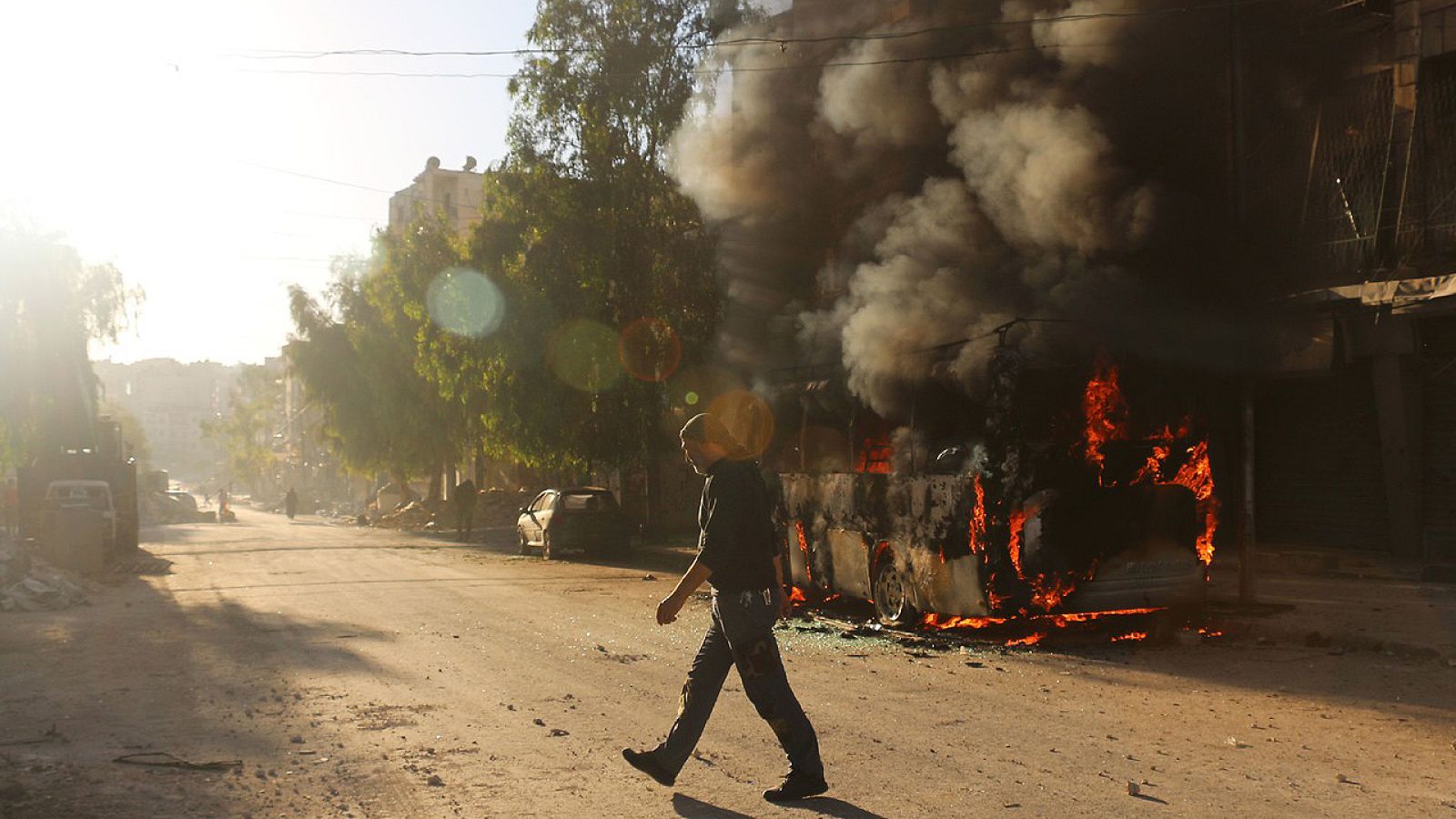 Un autobús arde tras un bombardeo en el barrio de Salahadin, en Alepo, Siria