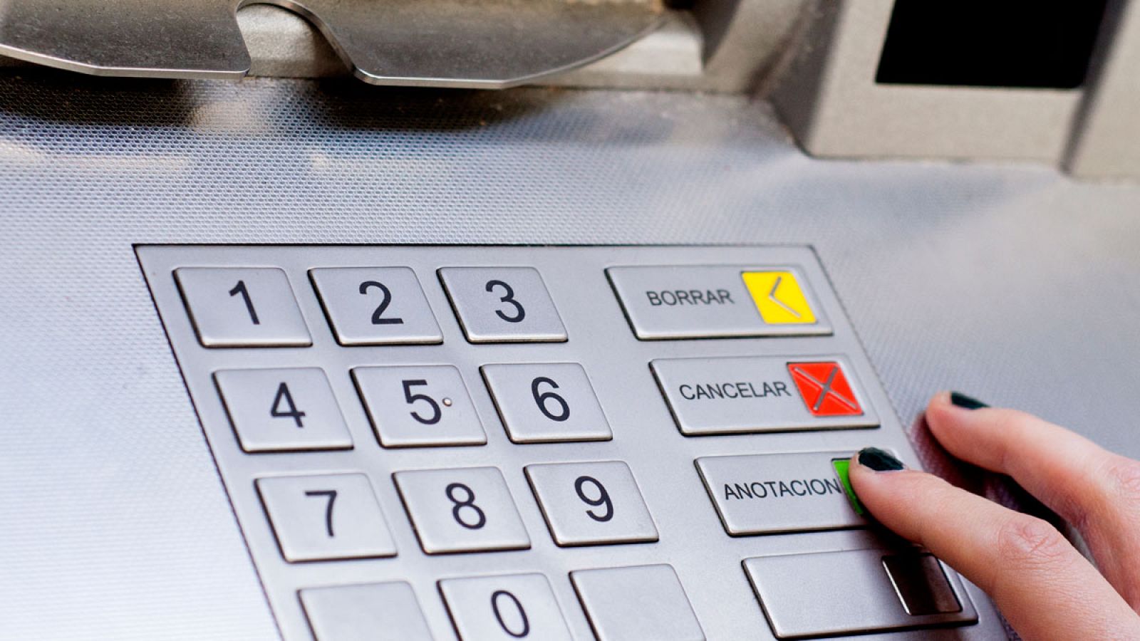 Una mujer saca dinero de un cajero automático