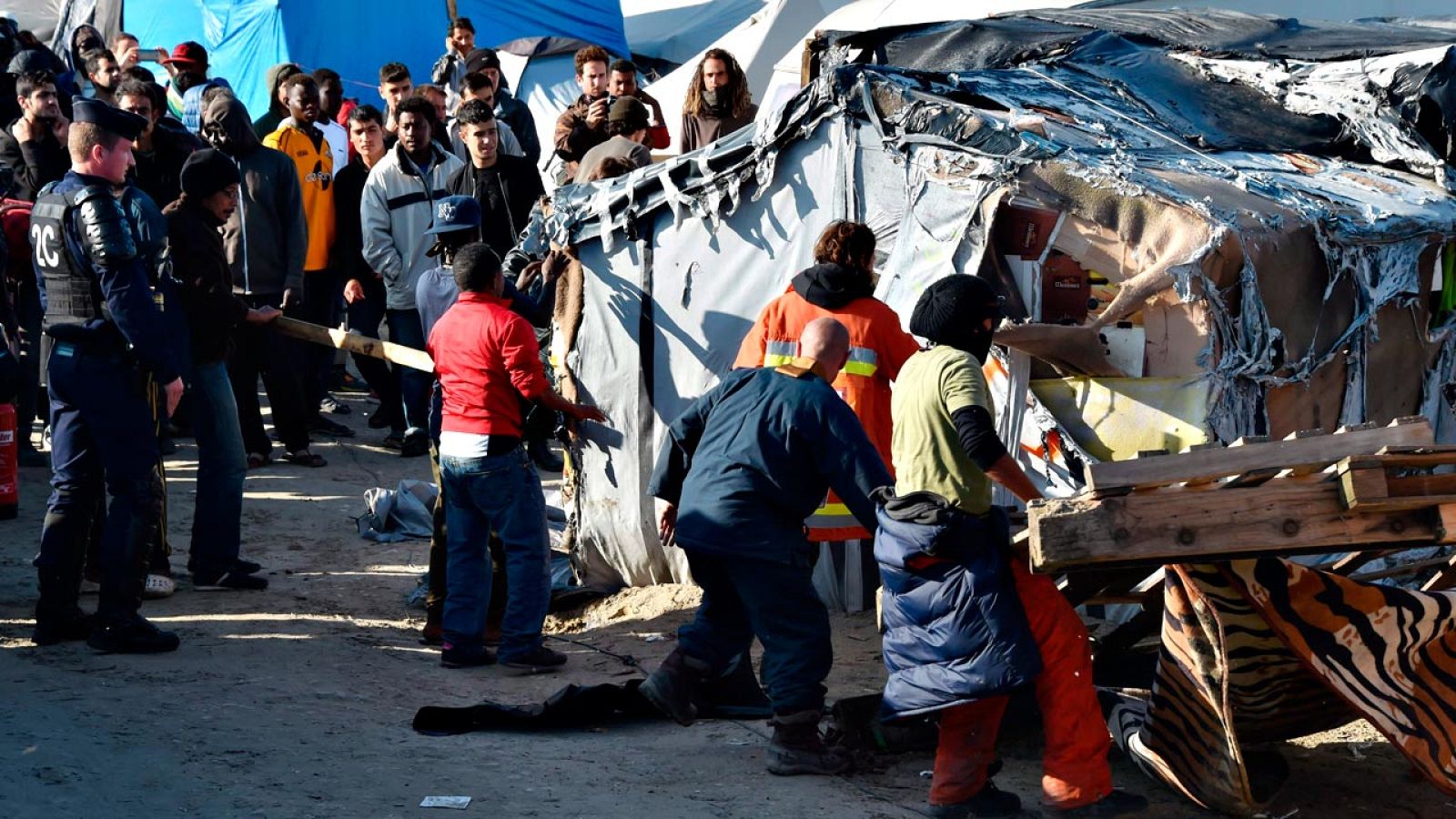 Los trabajos de desmantelamiento de la 'jungla de Calais', bajo la mirada de inmigrantes y fuerzas de seguridad