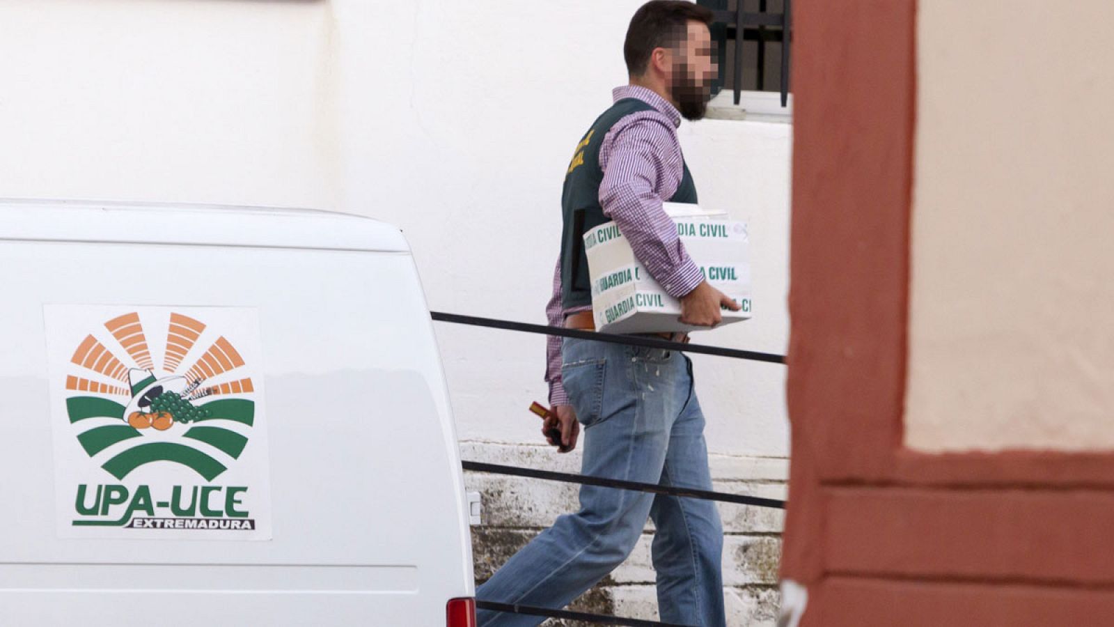 Un guardia civil sale con documentación de la sede central de UPA.UCE en Mérida