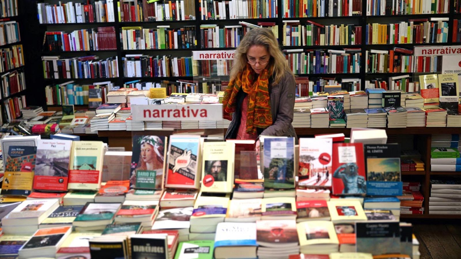 Una mujer hojea unos libros en una librería de Barcelona.